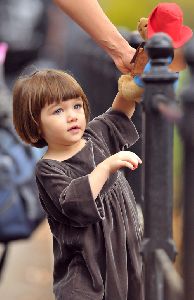 Suri Cruise : little Suri Cruise playing with her stuffed bear, dressed wearing a grey velvet dress having in Union Square Park. She was accompanied by mom Katie and bodyguards