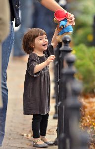 Suri Cruise : Suri Cruise playing with her stuffed bear, dressed wearing a grey velvet dress having in Union Square Park. She was accompanied by mom Katie and bodyguards