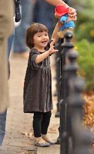 Suri Cruise : Suri Cruise playing with her stuffed bear, dressed wearing a grey velvet dress having in Union Square Park