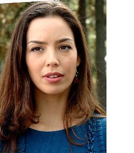 Azra Akin wearing a blue top and a red gem earrings