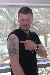 Kivanc Tatlitug pointing to his arm tattoo