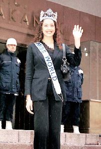 Azra Akin wearing a black suit and the crown of the crown of Miss world