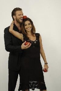 Songul Oden laughing with Kivanc Tatlitug both wearing formal black outfits