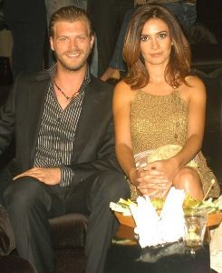 Songul Oden wearing a golden dress accompanied with Kivanc Tatlitug