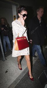 VICTORIA BECKHAM : arriving at Heathrow airport in London, England weaing a double chest dotted white coat and a red glam bag with a dark-shaded sunglasses on the 30th of November, 2008