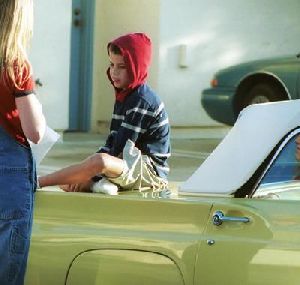 Jett Travolta sitting on a car's front