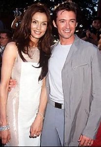 Actor hugh jackman standing beside a pretty woman that IS wearing a white dress.