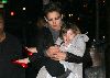 Suri Cruise : Katie is carrying Suri Cruise who is wearing a gray coat and shiny red ballerine flat shoes