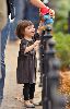 Suri Cruise : Suri Cruise playing with her stuffed bear, dressed wearing a grey velvet dress having in Union Square Park. She was accompanied by mom Katie and bodyguards