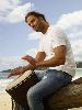 Josh Holloway : sitting on a tree trunk playing the drum