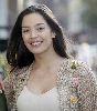 Azra Akin : smiling on the street to the camera wearing a beige knit jacket