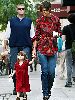 Suri Cruise wearing a dark red stylish dress accompanied by her mom and dad