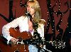 Liz Phair singing on stage and playing an accoustic guitar