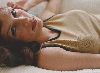 Famke Janssen : laying on a couch wearing a sleevless beige top