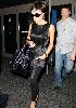 Victoria Beckham at Lax Airport wearing a dark satin mini-dress and black leggings